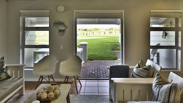 Una sala de estar con vista a un área verde a través de amplios ventanales.