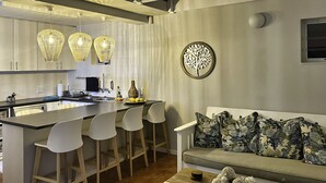 Una cocina moderna con una isla central, taburetes blancos y un sofá gris con cojines estampados.