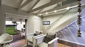 Un interior moderno con una escalera, una zona de estar con sillas y vistas al exterior.