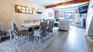 Un salon moderne avec un coin repas, comprenant une grande table, des chaises, un canapé et un téléviseur.