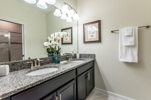 A bathroom with two sinks, dark cabinets, a large mirror, and framed artwork on the wall. - 6 Bed 5 Bath Pool & Game Room Champions Gate 6 Bedroom Villa by RedAwning (Davenport)