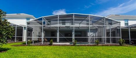 A modern house with a covered patio area, surrounded by a well-maintained lawn.
