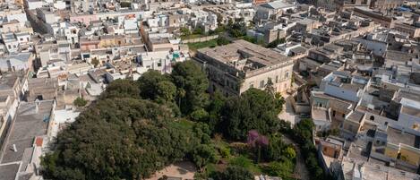 Vista aérea de una zona urbana densamente poblada con edificios residenciales y comerciales, rodeada de vegetación y un espacio abierto central.