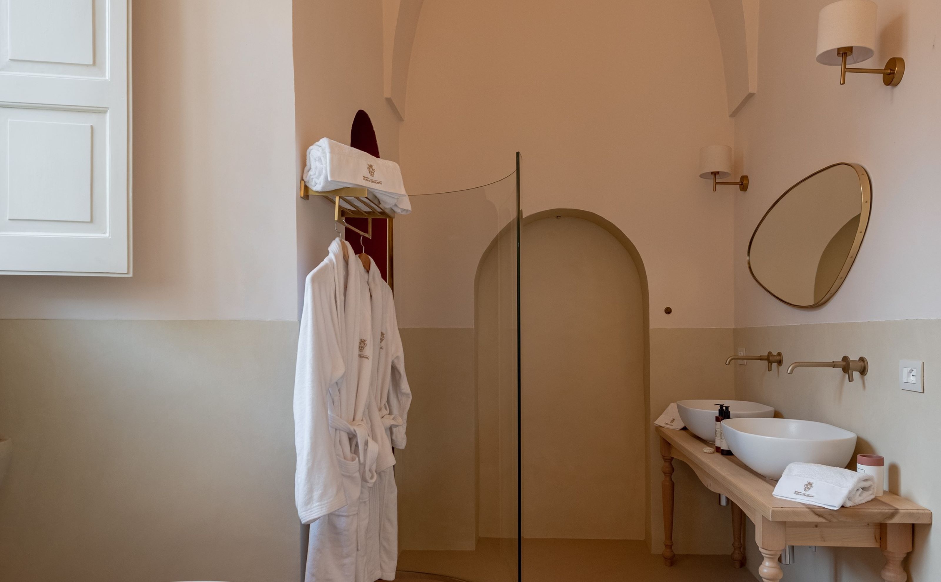A bathroom with a glass shower door, a white sink with a mirror above it, and a towel hanging on a rack.