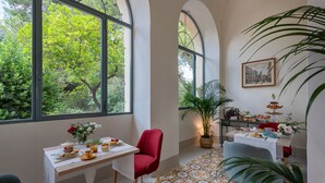 A dining area with a table set for breakfast, a red chair, and a potted plant. - Palazzo Donna Elisabetta -Guest House (Manduria)