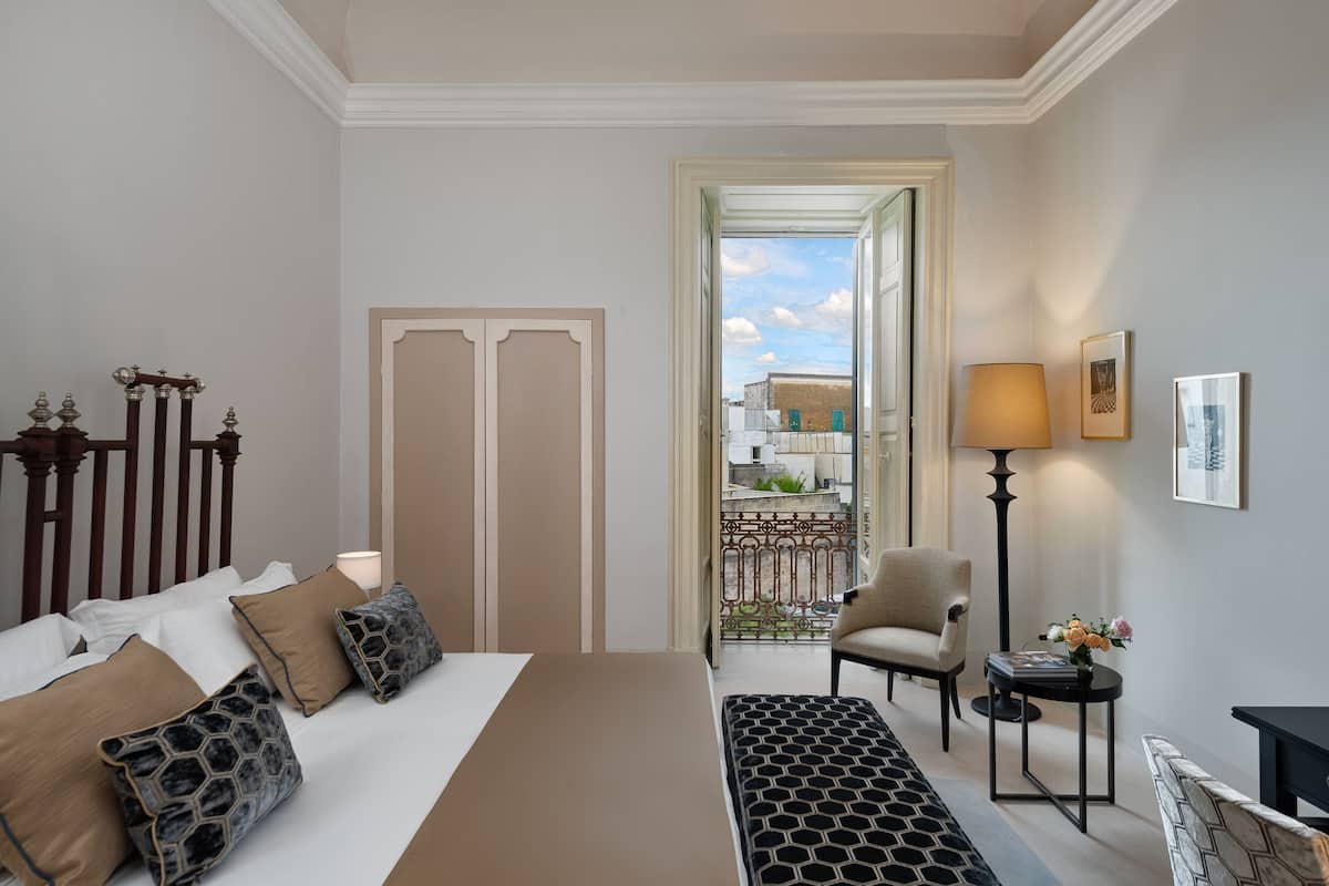 Ein Hotelzimmer mit Bett, Sessel, kleinem Tisch und Blick ins Freie.
