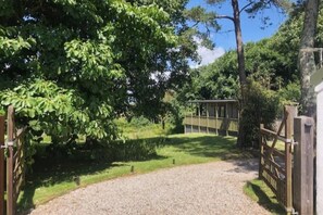 A gravel path leading to a wooden gate with a fence, surrounded by greenery and trees. - Longtails, beautiful lodge retreat Bantham S.Devon (Bantham)