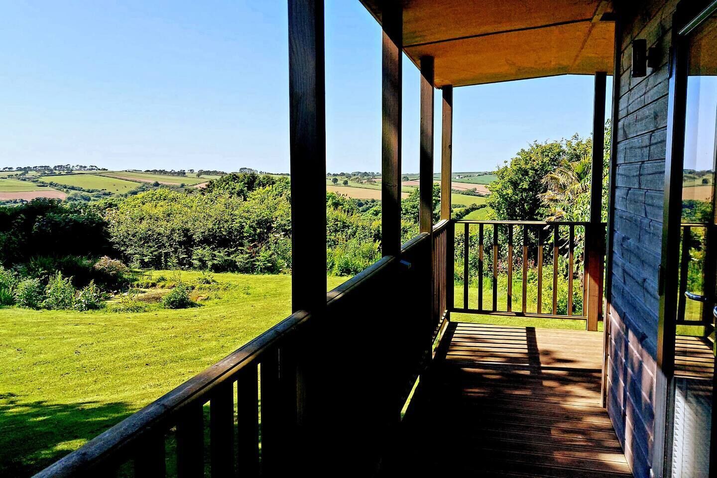 Un balcón de madera con vistas a un paisaje verde.