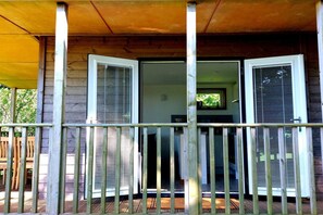 A wooden cabin with a porch, a door with a window, and a railing. - Longtails, beautiful lodge retreat Bantham S.Devon (Bantham)