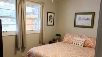 A bedroom with a bed, a ceiling fan, a window with curtains, and a rug.