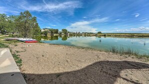 En vy över en sjö med båtar, en sandstrand och byggnader i bakgrunden.