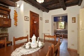 A dining room with a wooden table set for tea, a wooden cabinet, and a hanging fruit decoration. - Casa Le Meriche (Castiglione di Garfagnana)