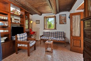Uma sala de estar com móveis de madeira, televisão, sofá e janela com vista.