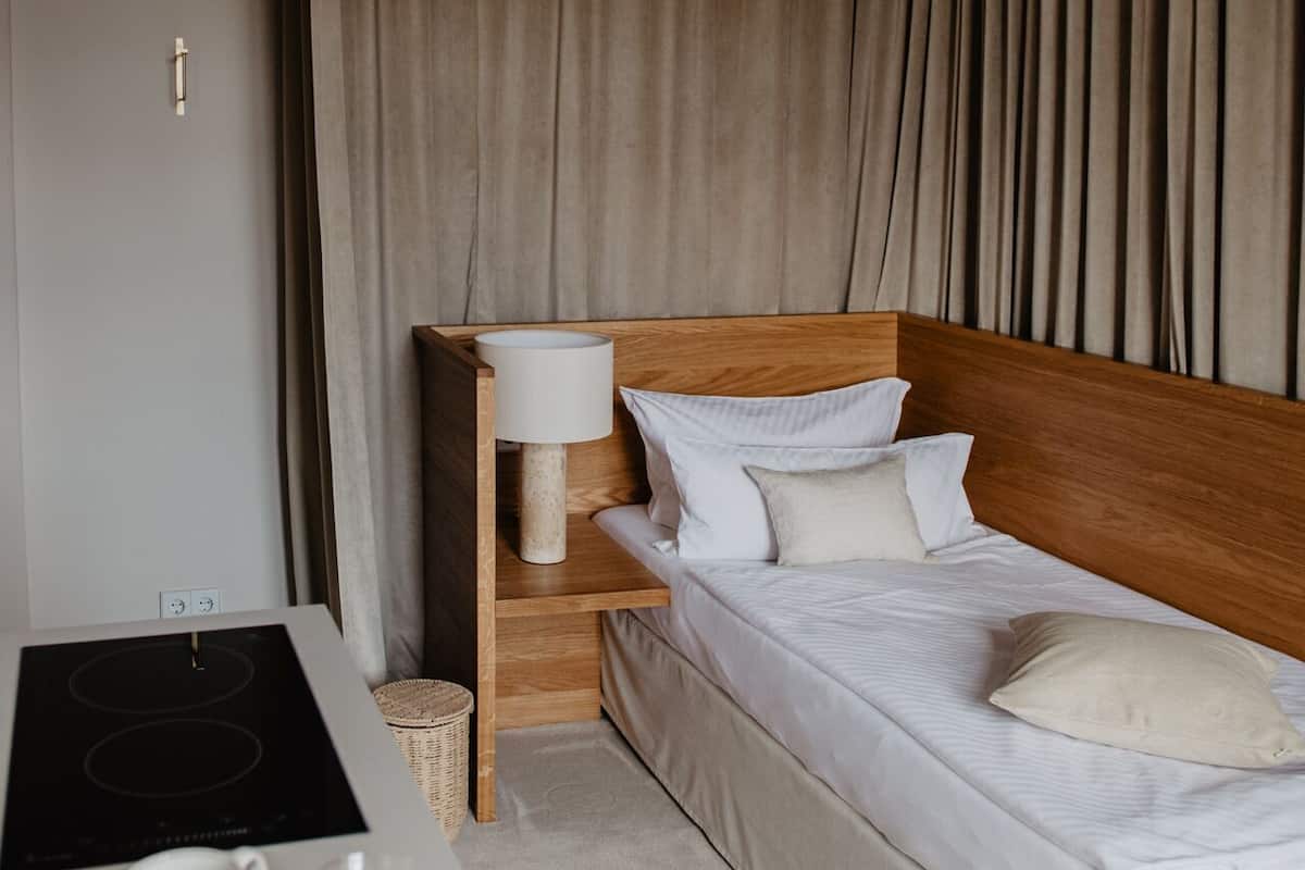 Una habitación de hotel con cama, mesita de noche, lámpara y una pequeña mesa con platos.