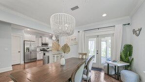 A spacious kitchen with white cabinets, a stainless steel refrigerator, and a chandelier. - Guest Favorite Beach Home*Golf Cart*Arcade*Bikes! (Inlet Beach)