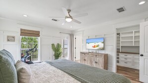 A spacious bedroom with a large bed, a ceiling fan, a television, and a walk-in closet. - Guest Favorite Beach Home*Golf Cart*Arcade*Bikes! (Inlet Beach)