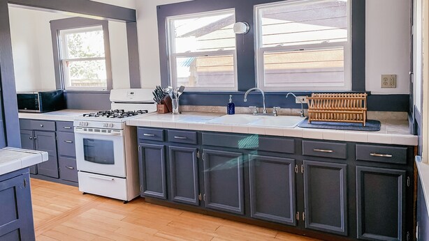 A modern kitchen with dark cabinets, a white stove, and a sink.