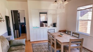 A cozy living area with a sofa, a dining table with chairs, a kitchen area with appliances, and a window providing natural light.