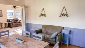 A cozy living room with a wooden dining table, a sofa, and two small side tables.