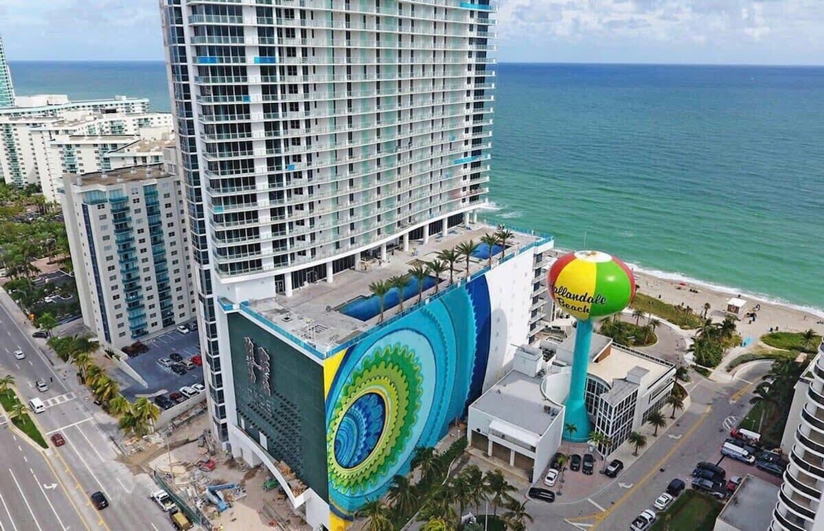 A high-rise hotel with a large mural on the side, a beach ball, and a view of the ocean.