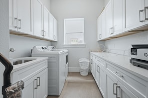 A laundry room with a washing machine, dryer, and stacked laundry baskets.