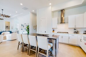 A modern kitchen with white cabinets, a central island with chairs, and a built-in stove. - Modern Chic 9 Bedroom Mansion Sleeps 20 with Themed Rooms at Reunion Resort (Kissimmee)