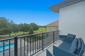 Ein Balkon mit Pool, Sitzgelegenheit im Freien und Blick auf einen Golfplatz.