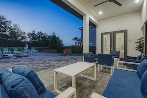 Uma área de estar ao ar livre com piscina, espreguiçadeiras e um espaço para sentar.