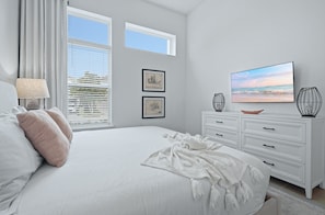 A bedroom with a large bed, a TV, and artwork on the wall.