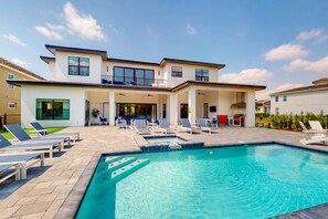 A two-story house with a swimming pool, lounge chairs, and a covered patio area. - Modern Chic 9 Bedroom Mansion Sleeps 20 with Themed Rooms at Reunion Resort (Kissimmee)