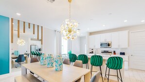 A modern kitchen with white cabinets, a microwave, and a dining area with a table and chairs.