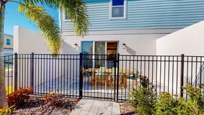 A house with a fenced patio, a dining area with a table and chairs, and a window with a view.