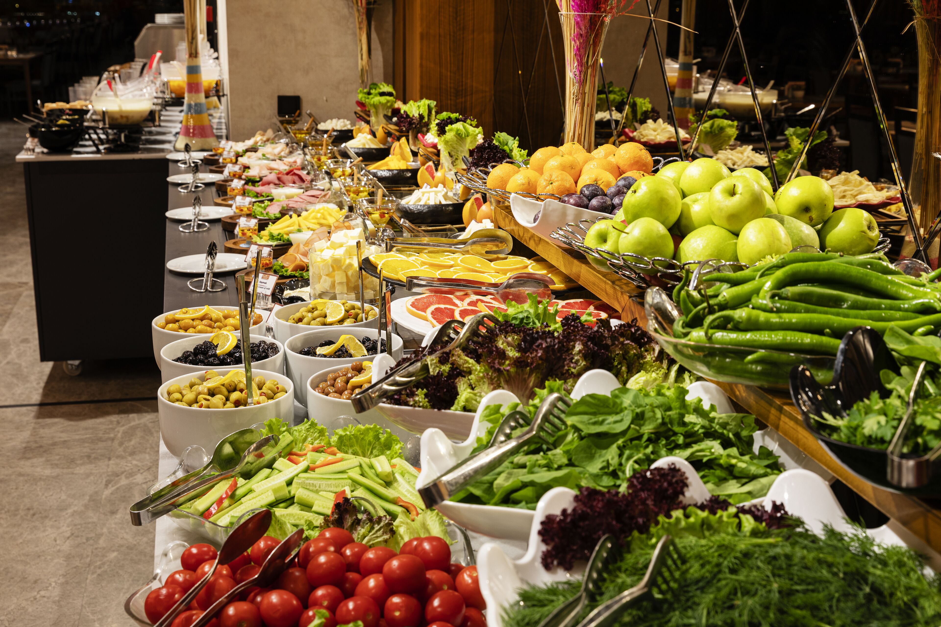 Un buffet proposant une variété de plats, notamment des fruits, des légumes et des salades.