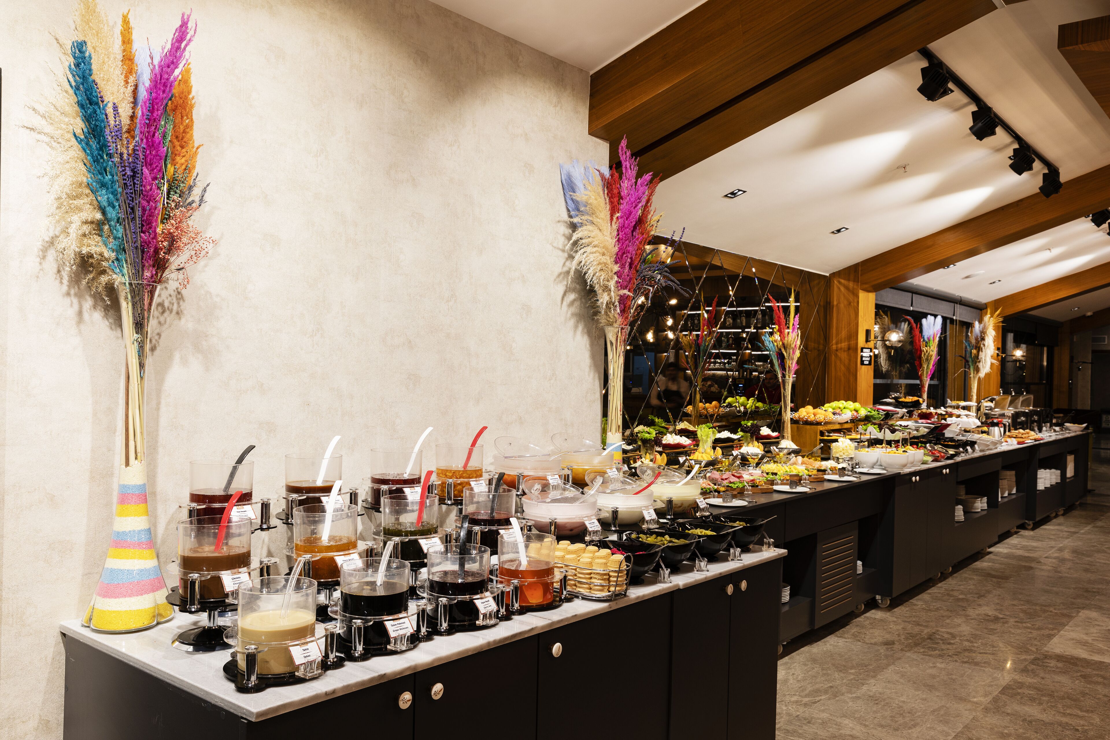 A buffet with various food items and beverages, and decorative plants.