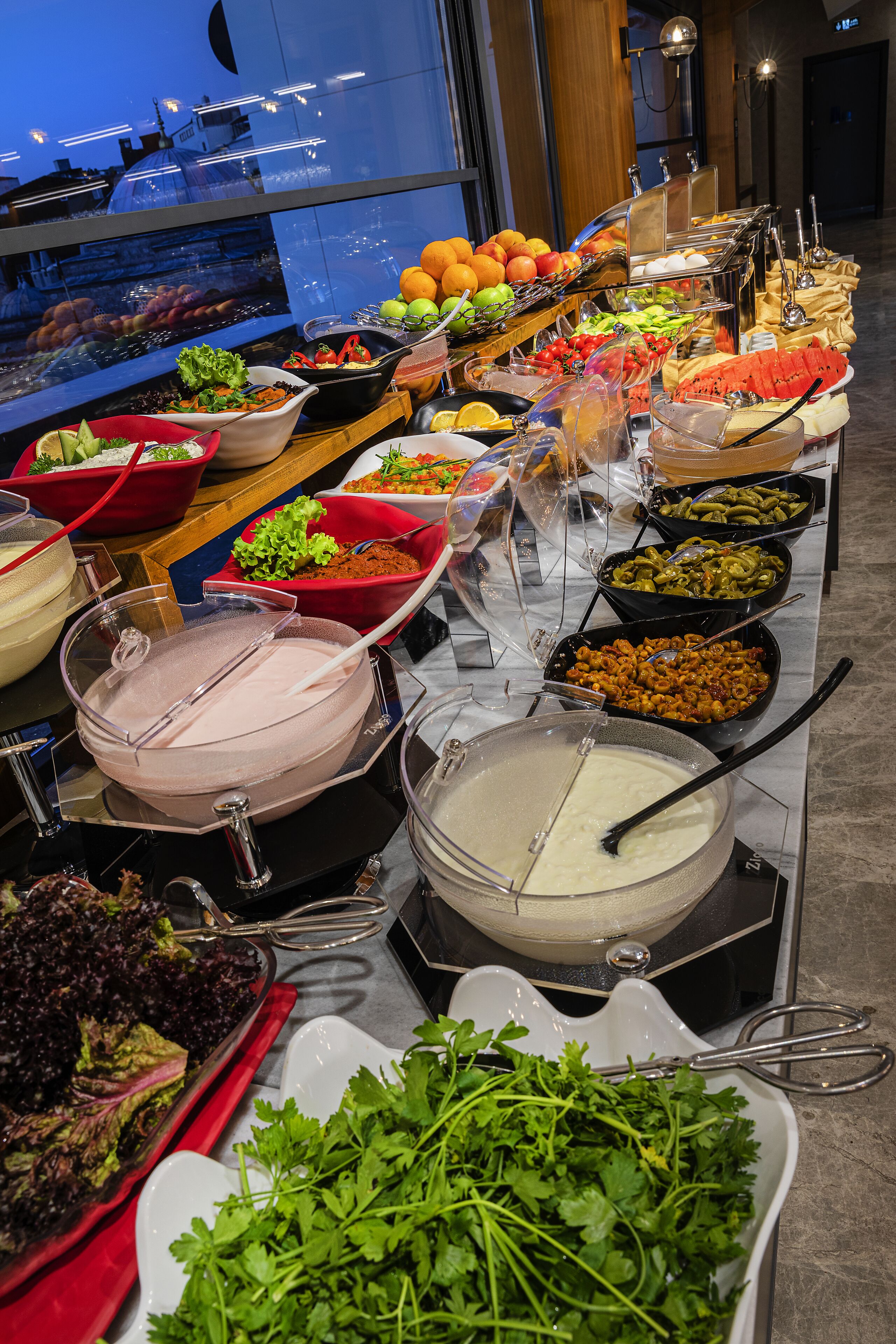 A buffet with various food options including fruits, vegetables, and dips.