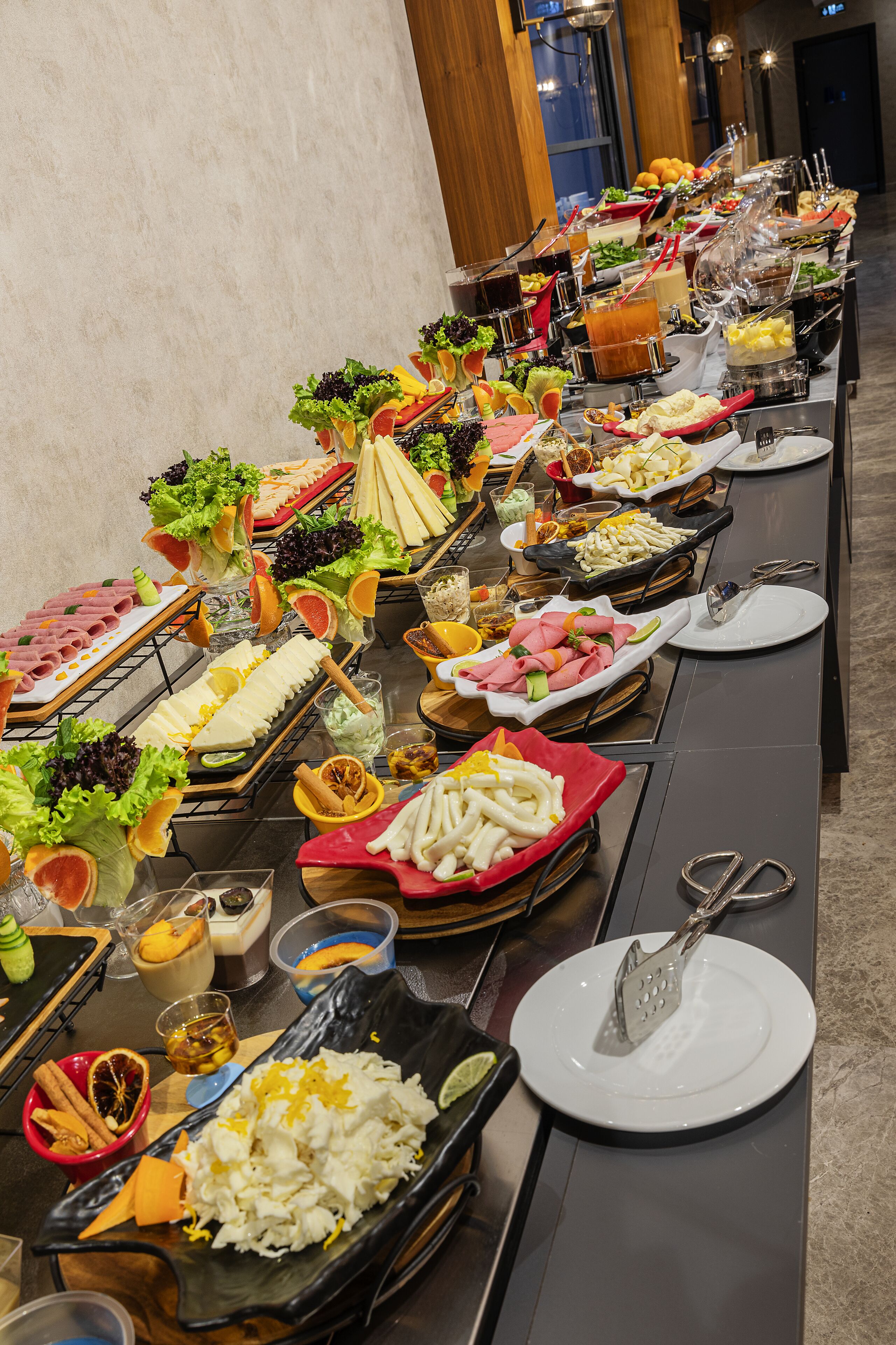 A buffet table with various food items and utensils.