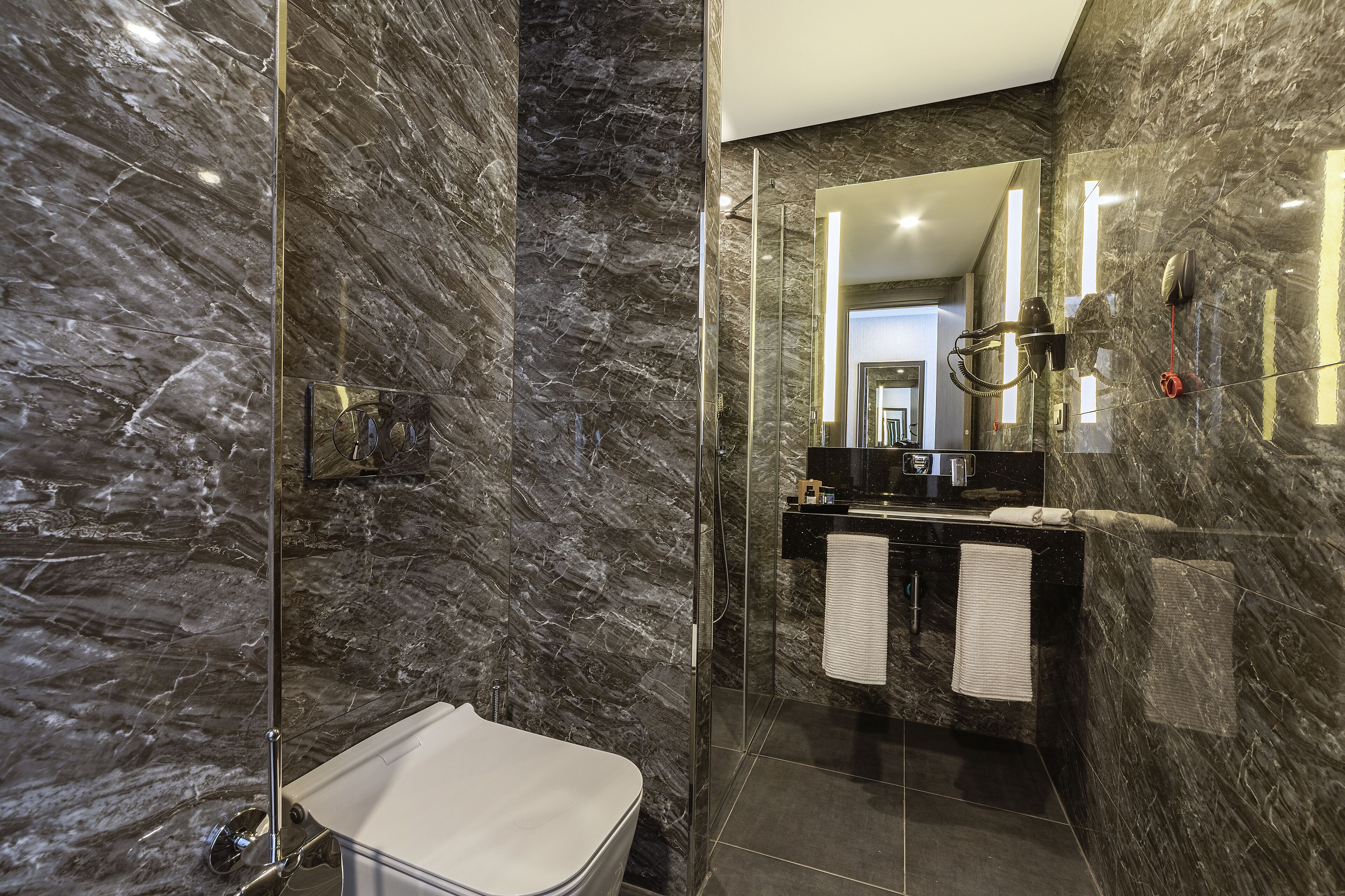 A modern bathroom with a glass-enclosed shower, a white sink, and a black vanity.