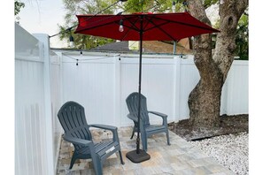Relax in a serene patio setting with Adirondack chairs under a shaded area.
