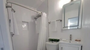 Un bagno con doccia, WC e lavandino.