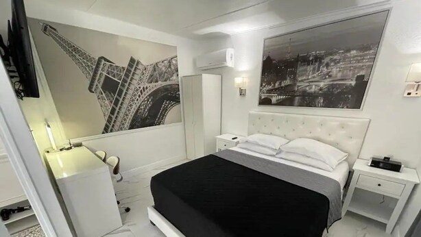 Una camera da letto con un letto, un comodino, una cassettiera, uno specchio e una parete con un quadro grande.
