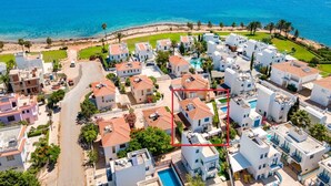 A coastal residential area with white buildings, a swimming pool, and a view of the sea. - Villa Serena Springs by Ezoria Villas (Protaras)
