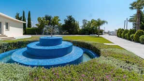 Una fuente circular con jardín bien cuidado, rodeado de diversas plantas y flores.