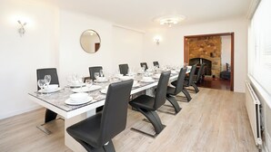 A dining room with a long table set for a meal, black chairs, a round mirror, and a stone fireplace. - Rentmyspahome With Swimming Pool, Hottub and Sauna (Sheffield)