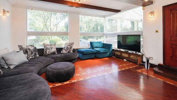 A spacious living room with a large sectional sofa, a blue accent chair, a flat-screen TV, and a wooden floor. - Rentmyspahome With Swimming Pool, Hottub and Sauna (Sheffield)