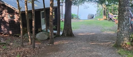 Ein rustikales Blockhaus mit einem Schotterweg, der zu einem Steg an einem See führt.