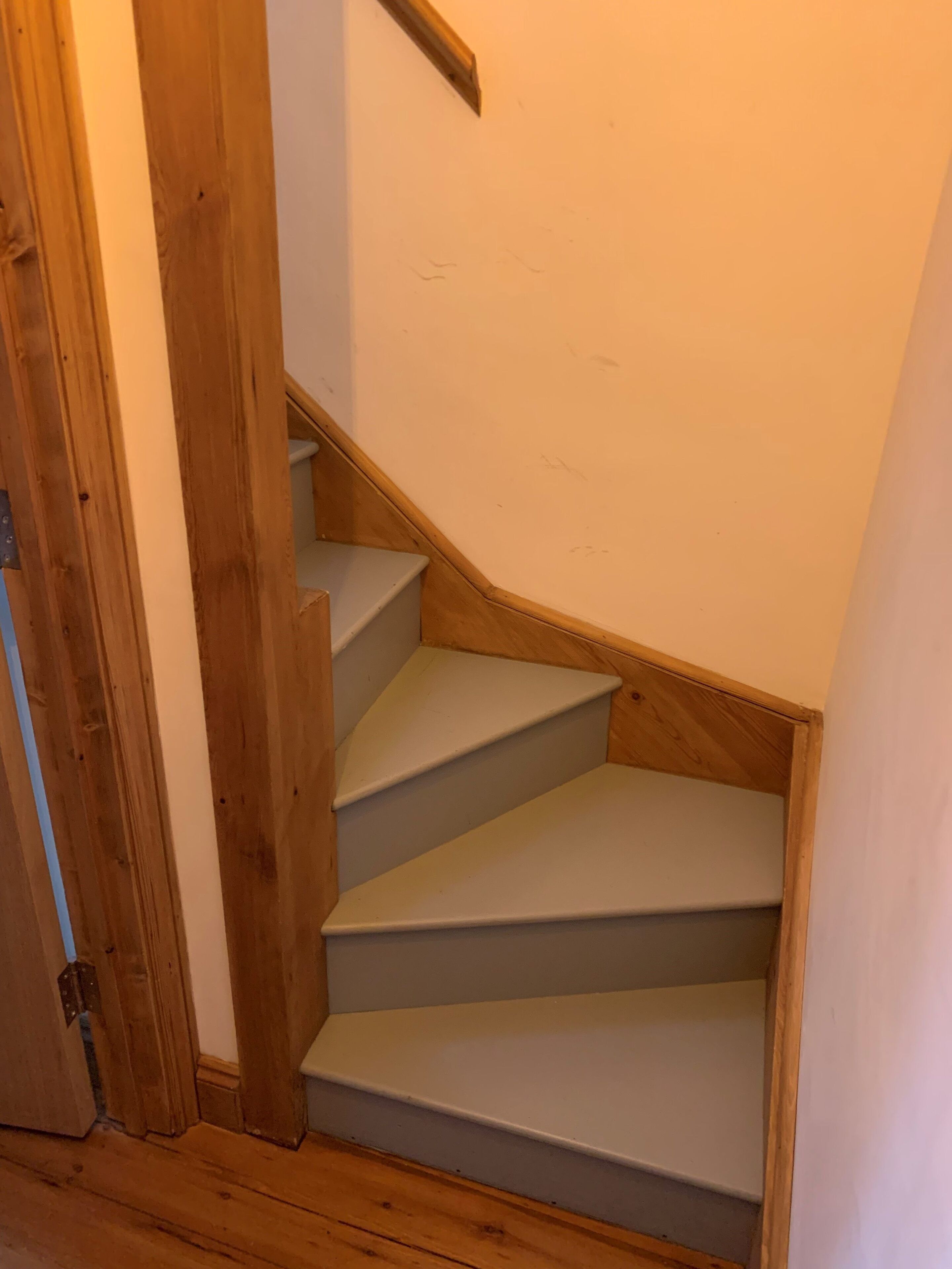 A wooden staircase with white steps leading to a landing.