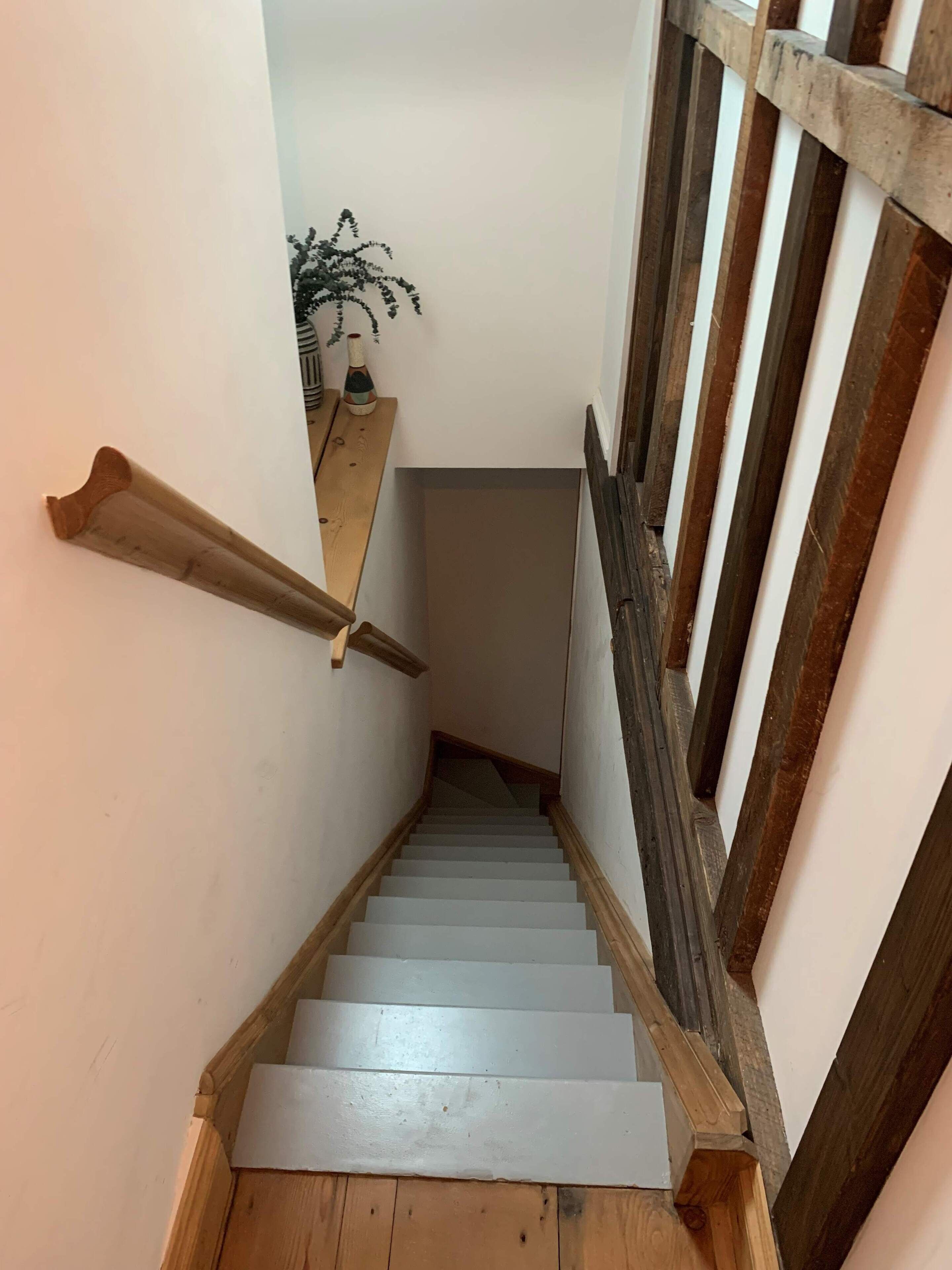 Una escalera de madera con barandilla a la derecha y un borde de madera a la izquierda.