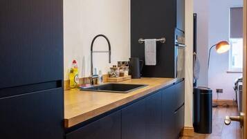 A modern kitchen with dark cabinetry, a wooden countertop, and a sink.