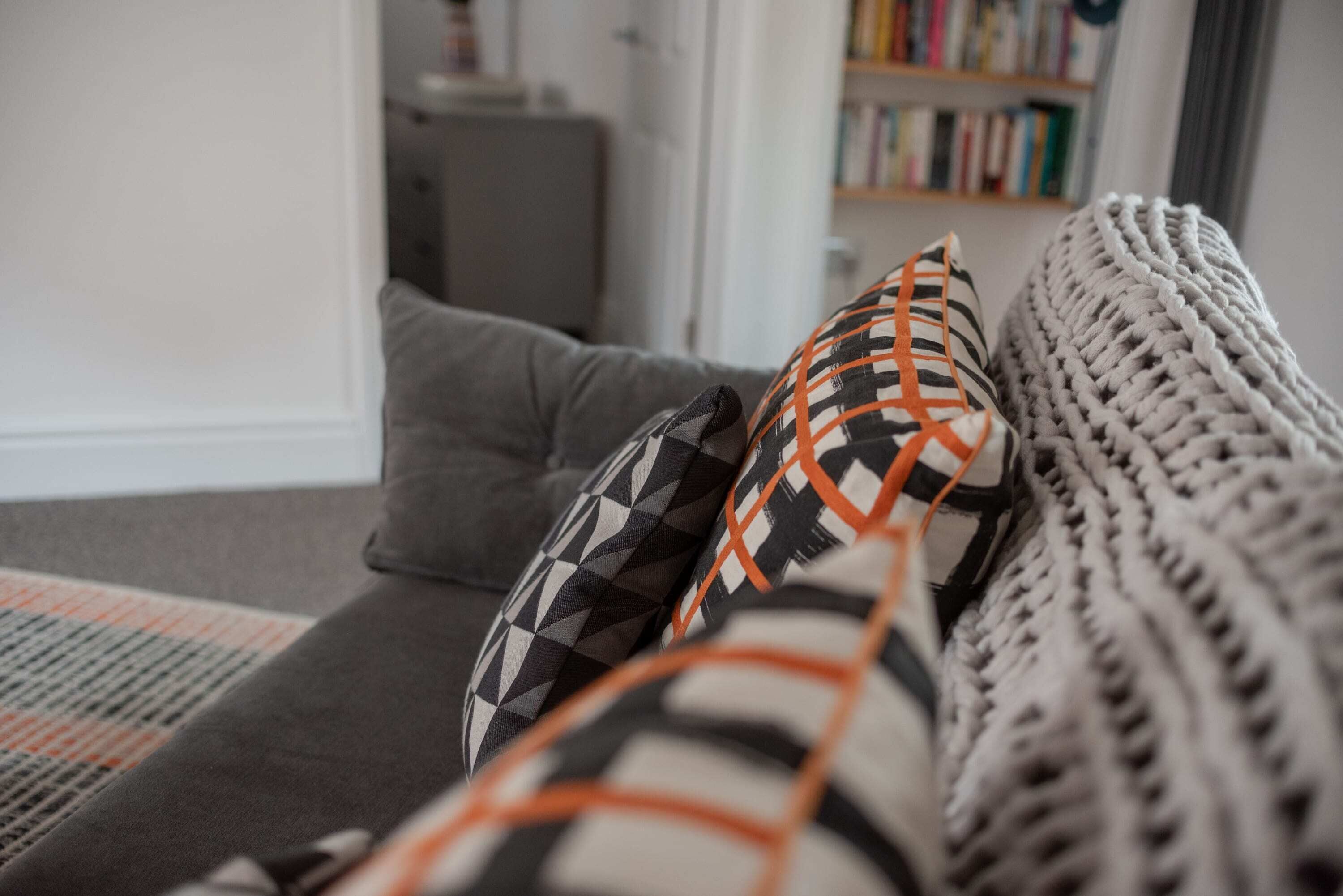 Ein Detailaufnahme eines Sofas mit gemusterten Kissen und einer gestrickten Decke.