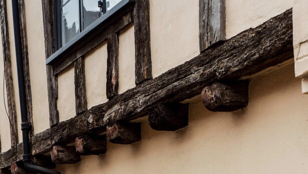 A building with a black door and windows, a stone foundation, and a timber-framed upper story. - Grade II Listed Flat with Modern Touches Sleeps 2 (Norwich)